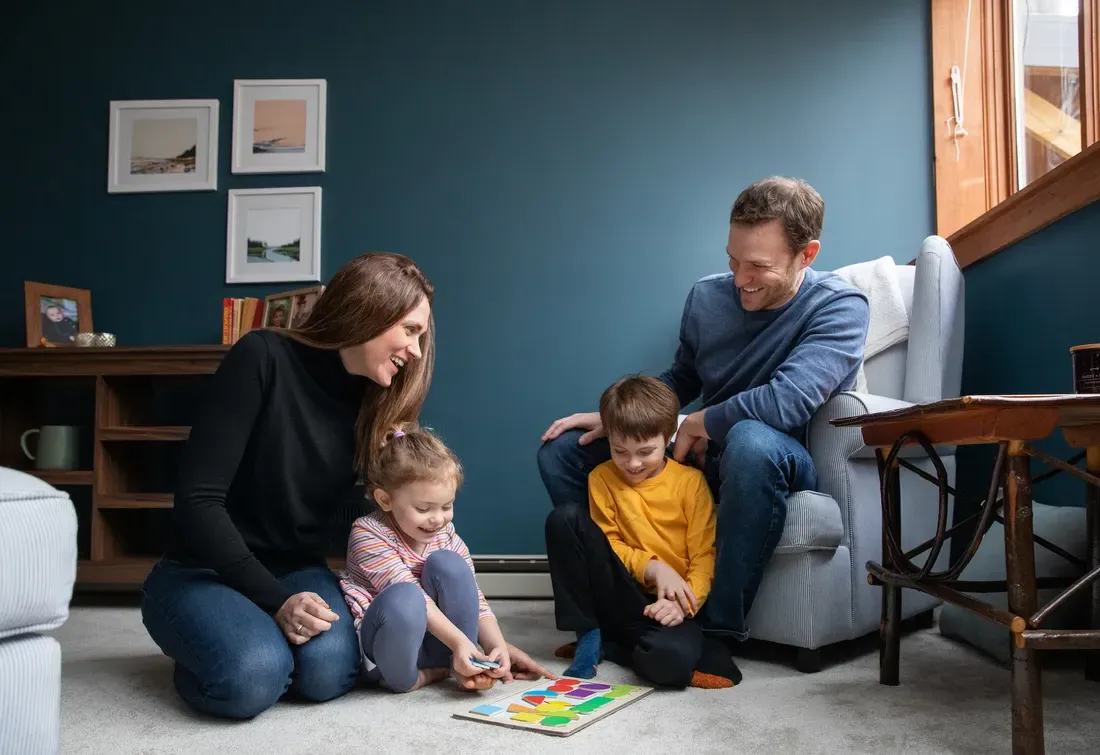 两个大人和两个孩子坐在一个房间里，在地板上玩游戏.